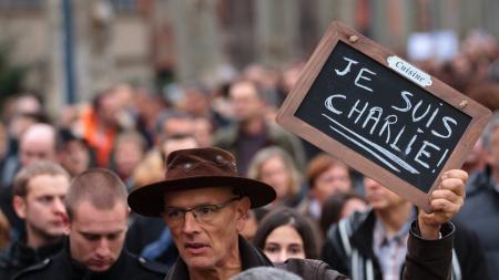 Crowd of people at a march, one man holds a sign that reads "Je suis Charlie"